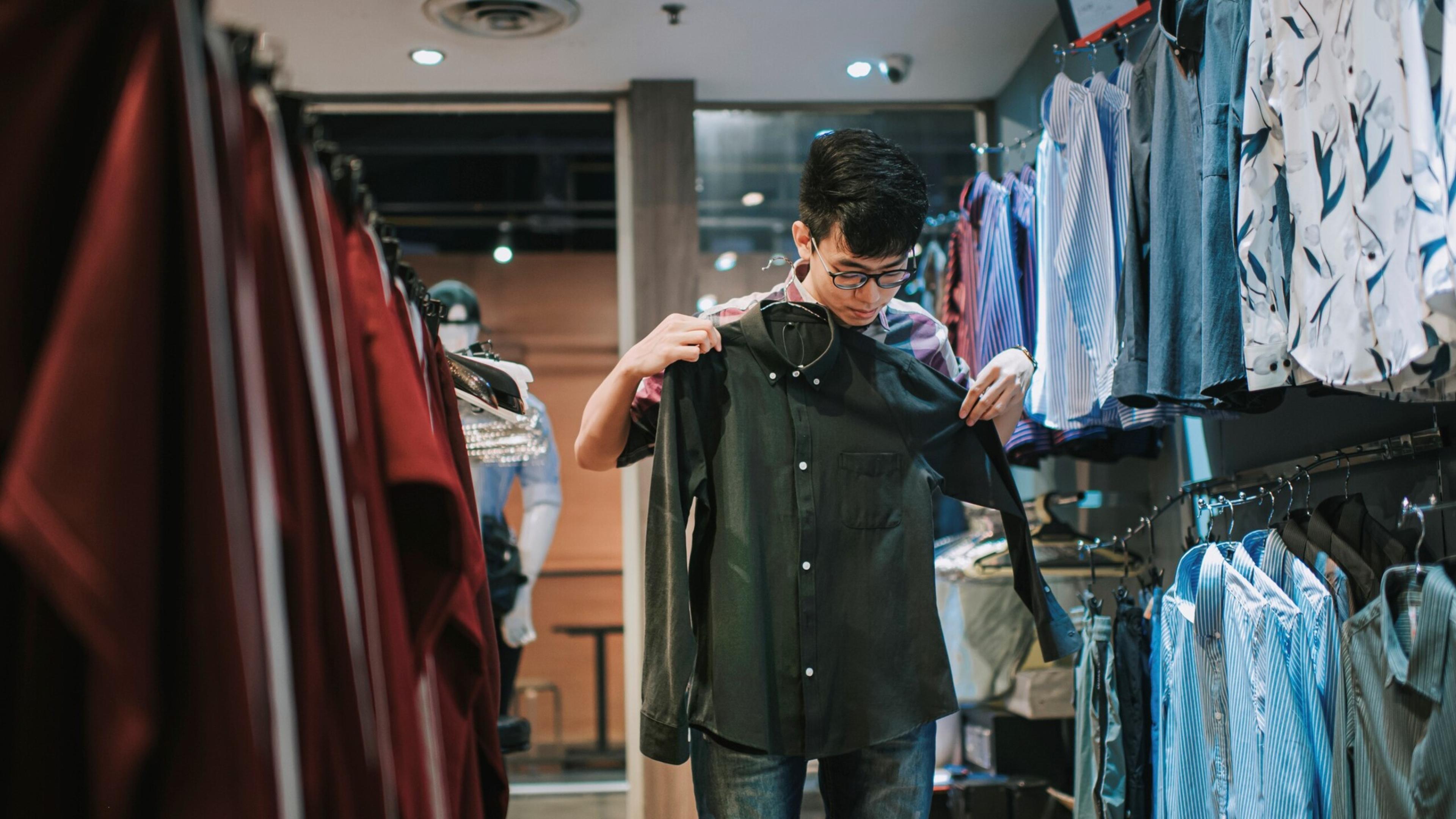 Young man trying on a shirt in store