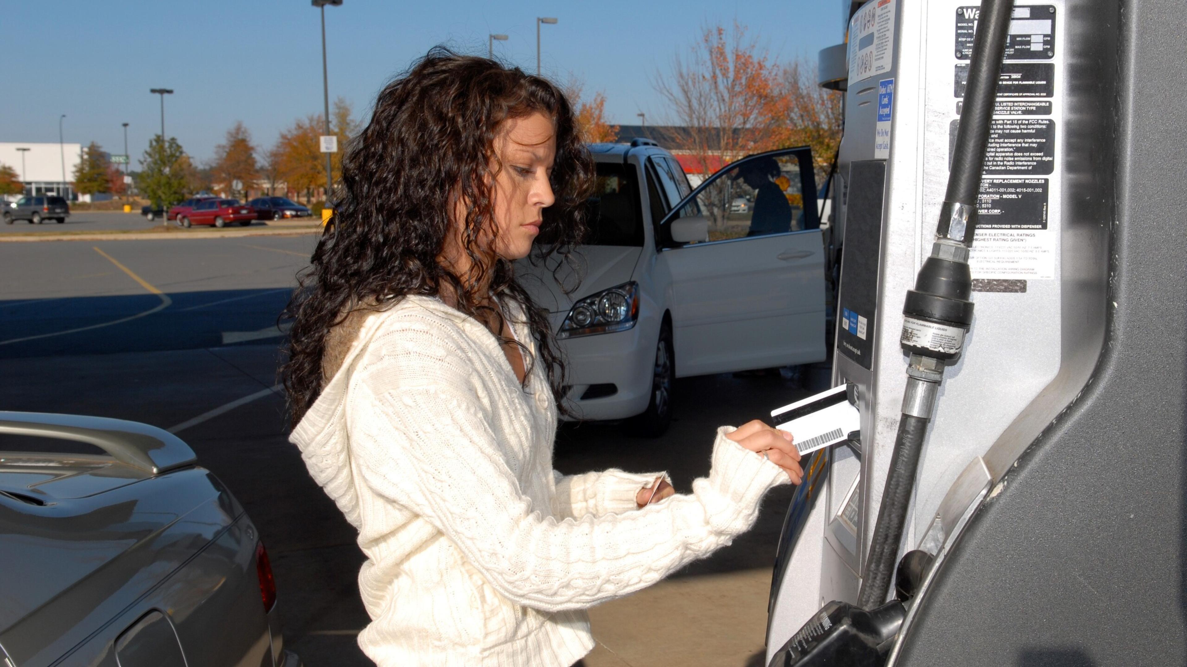 Young woman paying for gas at the pump